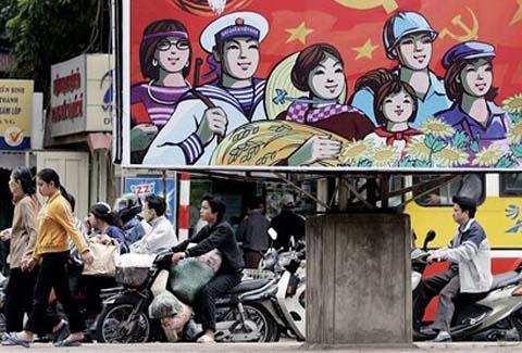 Vietnamese ride past a giant poster featuring the upcoming national  Communist Party Congress of Vietnam in Hanoi 